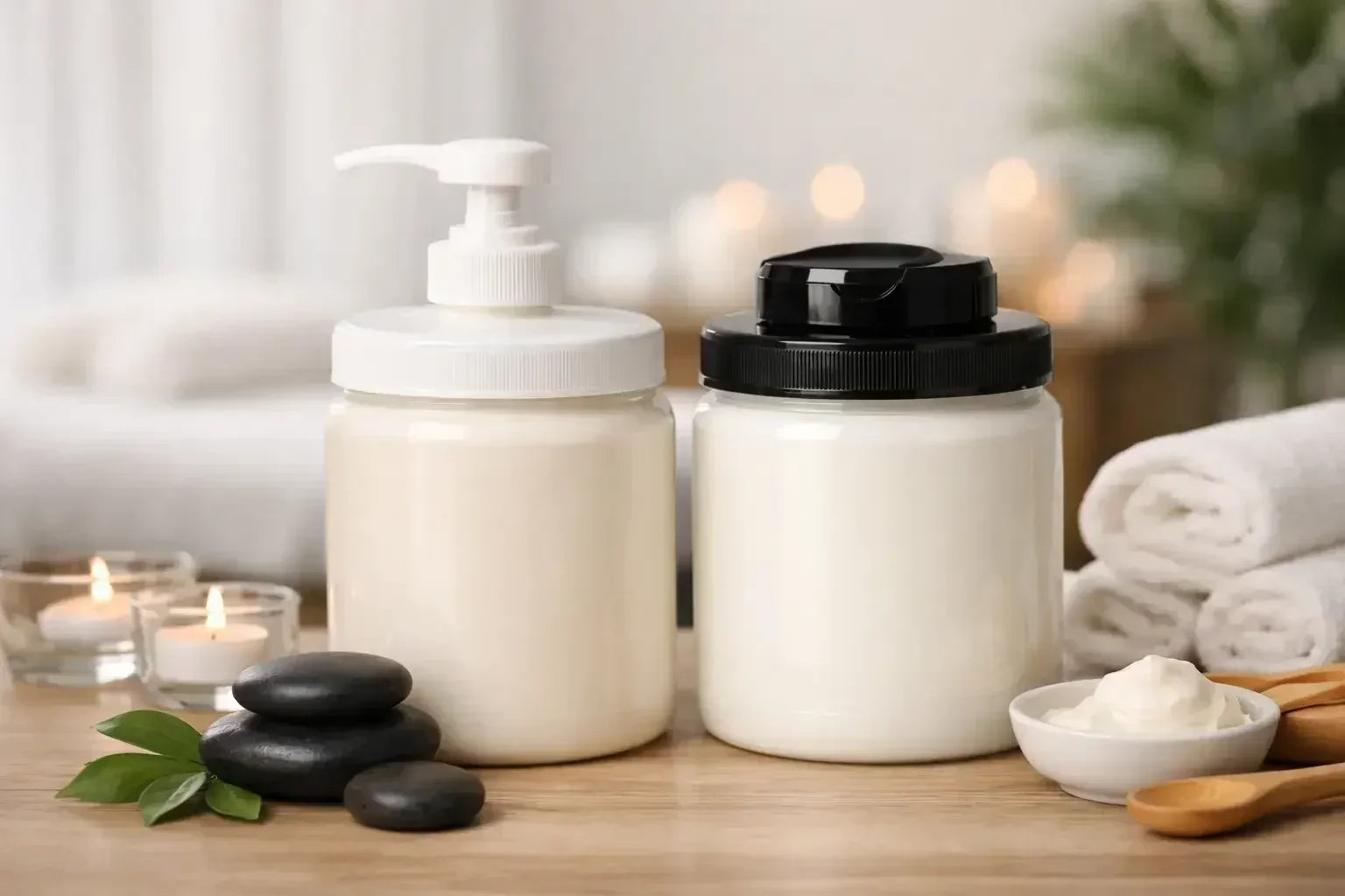 2 different massage cream in tubs sitting on a table with candles, stones, and towels to illustrate Biotone Advanced Therapy Cream vs Massage FX Cream