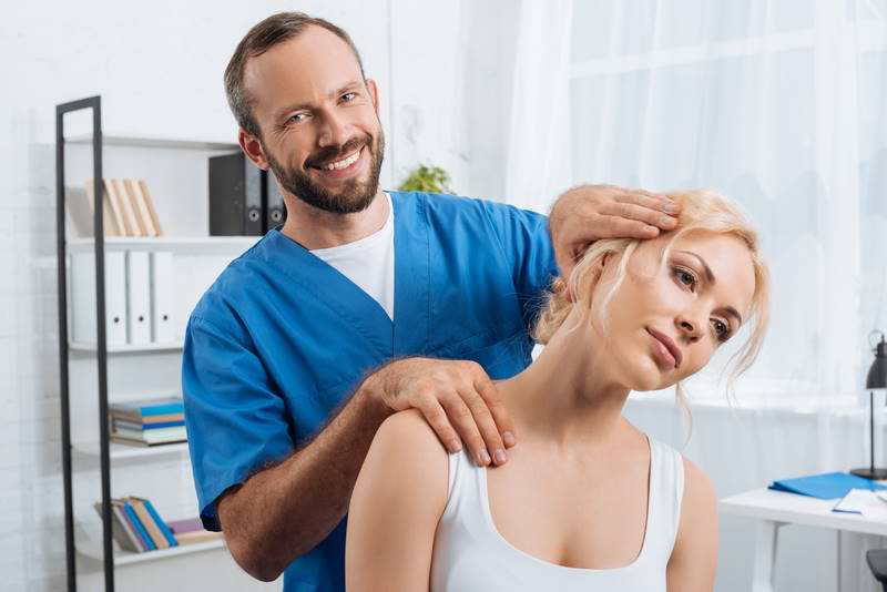 A chiropractor who is adjusting a patient in a medical office setting.