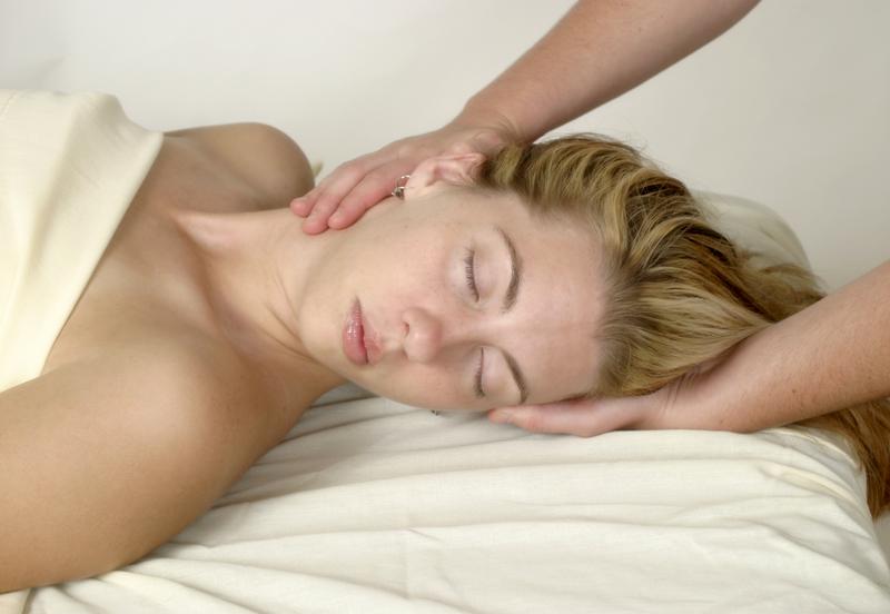 A lady on a table receiving neck and head therapy work.